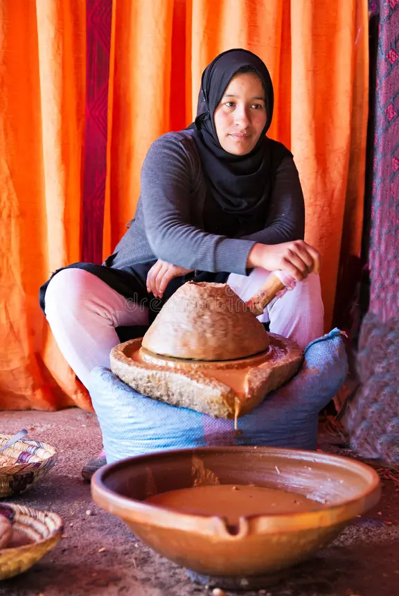 Moroccan woman grinding argan oil traditional stone mill Souss
